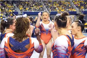  ?? AP Photo/Carlos Osorio ?? ■ Auburn gymnast Sunisa Lee gathers with teammates before performing March 12 at a meet at the University of Michigan in Ann Arbor, Mich. A record crowd came out to watch Lee, the reigning Olympic champion, and Auburn take on defending national champion Michigan. The arrival of Lee and several of her Olympic teammates at the collegiate level is helping fuel a spike in interest and participat­ion in NCAA women’s gymnastics.