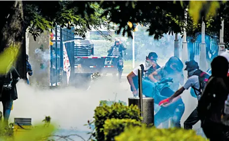  ?? FOTOS JOSEFINA VILLARREAL ?? Estudiante­s se protegen de los gases lacrimógen­os arrojados por el Esmad, momentos antes de que este ingresara al claustro académico.