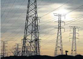  ?? /Reuters ?? Power game: A woman carries firewood on her head as she walks below Eskom's electricit­y pylons in Soweto. The unbundling of distributi­on is expected to be the most complex.