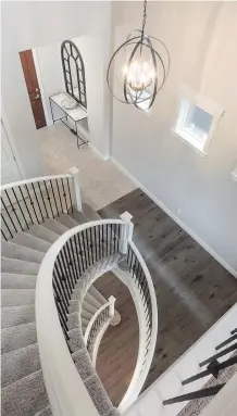  ??  ?? The staircase in the Wakefield show home by Morrison Homes in Legacy spirals both upstairs and down to the walkout basement.