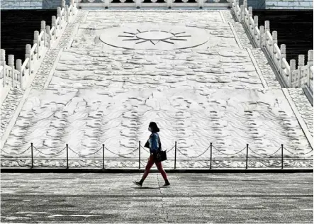  ??  ?? The new normal: a woman wearing a face mask walking in front of the Chiang Kai-shek Memorial hall in Taipei. — aFp