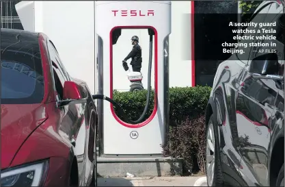  ?? — AP FILES ?? A security guard watches a Tesla electric vehicle charging station in Beijing.