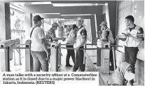  ?? (REUTERS) ?? A man talks with a security officer at a Commuterli­ne station as it is closed due to a major power blackout in Jakarta, Indonesia.