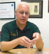  ?? DAVID BOWMAN/NASA ?? Robert Bryant in his NASA Langley Research Center office holding examples of wires used in heart devices; a material he discovered is used as insulation.