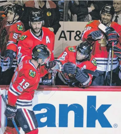  ?? | AP ?? Hawks captain Jonathan Toews is congratula­ted by teammates after scoring in the shootout Friday against the Islanders.