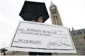  ?? JUSTIN TANG / THE CANADIAN PRESS ?? A protester holds a novelty cheque made out to Kinder Morgan at a rally on Parliament Hill in Ottawa on Tuesday against the proposed Trans Mountain pipeline project.