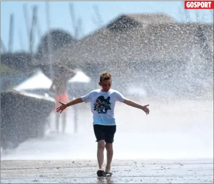  ??  ?? GOSPORT SPRAYING FOR RAIN: A boy gets soaked at Stokes Bay near Gosport in Hampshire as winds hit the harbour