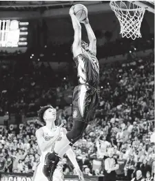  ?? Matt Stamey / Associated Press ?? Florida State guard Devin Vassell flies in for a dunk past Florida’s Tre Mann during the first half of Sunday’s game.