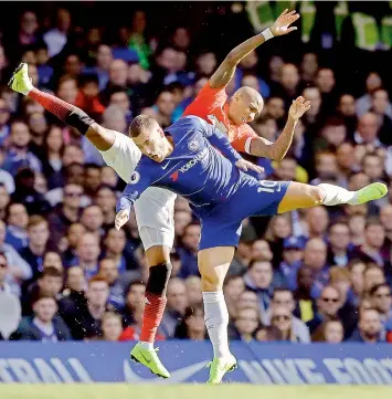  ?? —AP ?? Manchester United midfielder Ashley Young (in red) and Chelsea’s Eden Hazard clash as they vie for the ball during their English Premier League match at Stamford Bridge stadium in London on Saturday. The match ended 2-2.