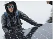  ?? JUSTIN SULLIVAN GETTY IMAGES ?? Pam Quan installs a solar panel on the roof of a home Wednesday in San Francisco.