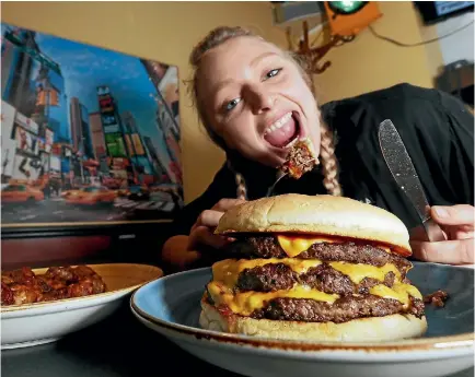  ?? PHOTO: TETSURO MITOMO/FAIRFAX NZ ?? Virginia Nicolson shows off the cafe’s new Meet the Reaper chilli burger and side of fiery chicken wings.