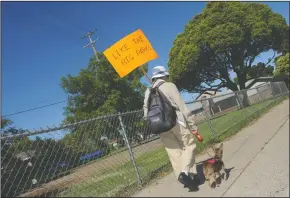  ?? BEA AHBECK/NEWS-SENTINEL ?? Lodi resident Myrna Wetzel pickets along Candy Cane Park on Holly Drive with her dog, Blessed, in Lodi on Thursday. She wants the city to replace the playground equipment in the park, which was removed two years ago. Only two swings remain in the small...