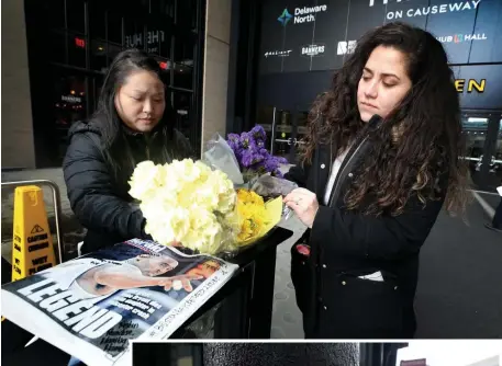  ?? NANCY LANE PHOTOS / HERALD STAFF ?? HEARTFELT TRIBUTE: Barbara Isaac and Maria Ordonez, both originally from Los Angeles, place yellow and purple flowers outside the TD Garden on Monday as a way to pay their respects after hearing of the death of Kobe Bryant. They also wrote messages on the cover of the Boston Herald that covered his death.