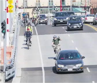 ?? DARREN STONE, TIMES COLONIST ?? Cyclists and drivers cross the new Johnson Street Bridge. Columnist Steve Wallace notes that the skill level of cyclists riding at different times of day seems to vary widely.