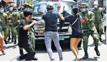  ?? (Ali Vicoy) ?? A MOTHER’S GRIEF – Donning protective equipment, detained activist Reina Mae Nasino (right photo) quietly weeps as her three-month-old baby River is laid to rest at the Manila North Cemetery on Friday, October 16. Left photo shows activists getting into a scuffle with policemen during the funeral march.