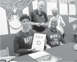  ?? JOE CAVARETTA/SUN SENTINEL ?? Forest Hill dual-sport athlete Donovan Draper signs a letter of intent to play football at the U.S. Naval Academy on Tuesday at Forest Hill High School in West Palm Beach. At right is his father Tony Watson, who is the basketball coach at the school.