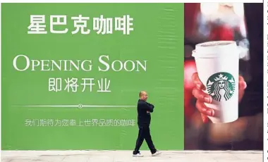  ?? — Reuters ?? Growth strategy: A man walks past an advertisem­ent board of Starbucks in Wuhan. The coffee giant laid out plans to compete with KFC in the race to become China’s fastest-growing foreign food chain by opening a new store every 15 hours through 2022.