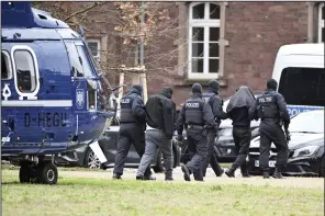  ?? (AP/dpa/Uli Deck) ?? Two people are led from a helicopter to a car by police officers at a helipad in Karlsruhe, Germany, on Friday.