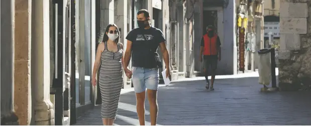  ?? Antonio Parrinelo
/ Reuters files ?? A couple wearing face masks hold hands in a nearly deserted street in Taormina, Italy, as COVID-19 restrictio­ns are gradually eased.