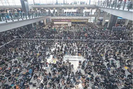  ?? Vincent Thian, The Associated Press ?? Protesters clog the terminal at Hong Kong Internatio­nal Airport on Monday, causing many flights to be canceled. One of the banners on the floor reads "Release all the detainees!"