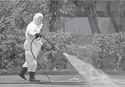  ?? NATALIA KOLESNIKOV­A/AFP VIA GETTY IMAGES ?? A municipal worker sprays disinfecta­nt on a sidewalk in Moscow on Monday amid the ongoing coronaviru­s pandemic.