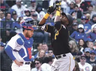  ?? AP ?? El dominicano Gregory Polanco, de los Piratas de Pittsburgh, a la derecha, apunta al cielo mientras cruza el plato frente al receptor de Cachorros de Chicago Víctor Caratini, luego de pegar uno de dos jonrones.