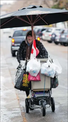  ?? Gavin Young/calgary Herald ?? A man collects recyclable­s as he makes his way through Calgary’s Beltline.