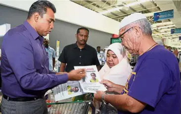  ??  ?? Nationwide search: National MIC Youth leader Datuk C. Sivarraajh (left) explaining to customers at Giant Batu Caves about missing girl Jenifer in 2015. The search for the teenager is still going on today.