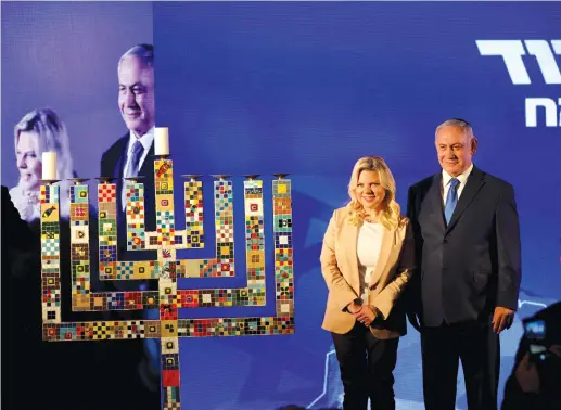  ?? (Corinna Kern/Reuters) ?? PRIME MINISTER Benjamin Netanyahu and his wife Sara attend a Likud Party gathering for the first night of Hanukkah on Sunday in Ramat Gan.