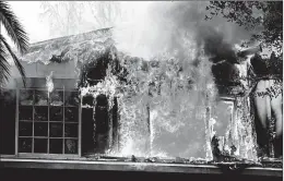  ?? RINGO H.W. CHIU/AP ?? A wildfire engulfs a home Friday near Malibu Lake in Malibu, Calif. One fire in Southern California scorched a historic movie site recently used by the HBO series “Westworld.”