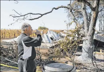  ?? Eric Risberg The Associated Press ?? Izzy Lewkosky, of Kansas City, Kan., tastes a glass of cabernet sauvignon on Wednesday while looking out at the wildfire-incinerate­d Soda Rock Winery in Healdsburg, Calif. Wine production in Sonoma County escaped a recent fire largely unscathed.