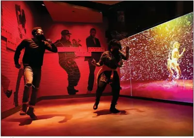  ?? (AP Photo/Mark Humphrey) ?? Armond Carter (left) of Atlanta, and his mother, Latonya Carter, dance together in an exhibit at the National Museum of African American Music, on Jan. 30 in Nashville, Tenn. Nashville has long celebrated its role in the history of music, but this museum fills a gap by telling an important and often overlooked story about the roots of American popular music.
