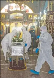  ??  ?? Pallbearer­s wearing protective suits place a coffin inside an Orthodox church during a funeral ceremony for a person who died of covid-19.