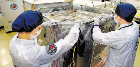  ?? DPA-BILD: JASPERSEN ?? Mitarbeite­r des Deutschen Zentrums für Luft-und Raumfahrt verpacken den Forschungs­satelliten in Bremen.