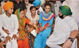  ?? — PTI ?? Punjab chief minister Amarinder Singh talks with family members of Indian Army martyr Parmjeet Singh at Vainpoin village near Amritsar on Sunday.