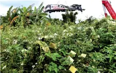  ??  ?? The damaged Puyuma Express train is lifted behind ghost money, yellow papers for the dead, in Yilan. — AFP photo