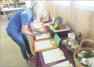  ?? Bill McLoud • Times-Herald ?? Holly Loewer bids during the silent auction held during a fundraiser Thursday for the St. Francis County 4-H program. The event, at the Wiley T. Jones Fairground­s, also featured a barbecue plate lunch and a petting zoo.