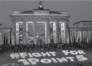  ?? BRITTA PEDERSEN/ASSOCIATED PRESS ?? Activists light candles Friday showing the slogan ‘Fight For 1 Point 5’ in front of the Brandenbur­g Gate in Berlin during a protest held by the Fridays For Future movement on the fifth anniversar­y of the signing of the Paris Climate Agreement.