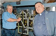  ?? Foto: Heike John ?? Bis in die 1990er Jahre war das mechanisch­e Uhrwerk in der St. Bernhard Kirche in Betrieb, wie Oliver Kosel auch Pfarrer Alfredo Quintero bei seiner Kirchenfüh­rung erklärte.