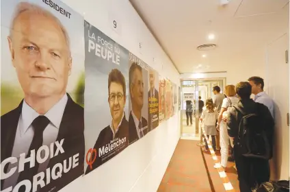  ?? Picture: Reuters ?? Posters of candidates line the walls as overseas voters line up outside a polling station during the first round of the French presidenti­al election in Hong Kong yesterday.