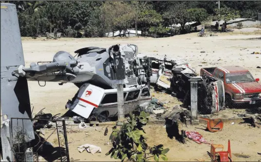  ?? Luis Alberto Cruz Hernandez The Associated Press ?? A downed helicopter lays on top of a van Saturday in Santiago Jimitepec, Mexico. The military helicopter carrying officials assessing damage from Friday’s 7.2 magnitude earthquake crashed, killing 13 people on the ground.