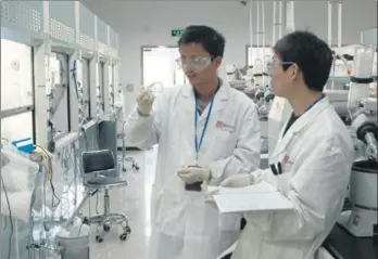  ?? PROVIDED TO CHINA DAILY ?? Two Chinese scientists (left) discuss use of equipment at the central chemistry lab of BeiGene in Beijing in May. A BeiGene scientist (right) examines a sample during a test.