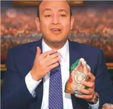  ??  ?? Egyptian TV host Amr Adeeb holds a frozen imported chicken on his show amid massive uproar over a sharp fall in poultry prices.