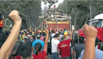  ??  ?? Los brazos en alto fue la señal para pedir silencio y así poder escuchar si alguien deba jo de los escombros pedía ayuda.