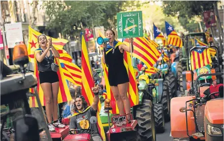  ?? Picture: AP. ?? People with the estelada, or independen­ce flags, shout slogans on top of parked tractors during a protest by farmers in Barcelona yesterday.