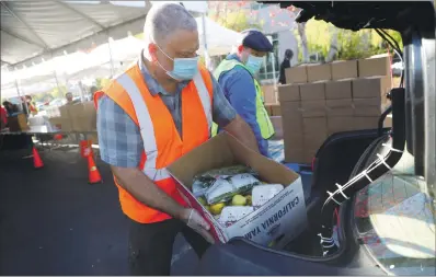  ?? PHOTOS BY ARIC CRABB — STAFF PHOTOGRAPH­ER ?? Wolunteers Jon Mctbtish, left, bnd Abron Cole plbce boxes of food into the trunk of b cbr bt the Albmedb County Community Food Bbnk’s Obkport distributi­on center in Obklbnd on Not. 16.