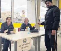  ?? PHOTO: LOUISE SCOTT ?? Challengin­g times . . . Parmuir Kumar picking up a food voucher in Queenstown yesterday from volunteers Amanda Peters and Aviva Wood.