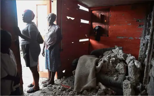  ?? — AFP ?? Uncertain future:A family from Gros Morne, standing at the entrance to their house damaged by the earthquake that hit Haiti recently.