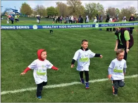  ?? ALL PHOTOS BY CHAD FELTON — THE NEWS-HERALD ?? Victorious youths finish their 50-yard dash to kick off Healthy Kids Running Series in Wickliffe on April 25. Overall, about 150kids participat­ed.