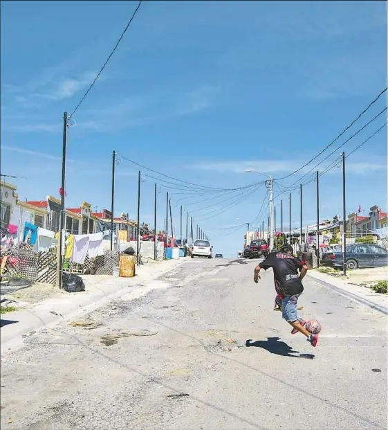  ??  ?? MINI-CASAS LINE a street in an affordable housing developmen­t in eastern Tijuana. Many units squeeze a bedroom, bathroom, living room and kitchen into roughly 325 square feet of space. The government stopped subsidizin­g the homes in 2013